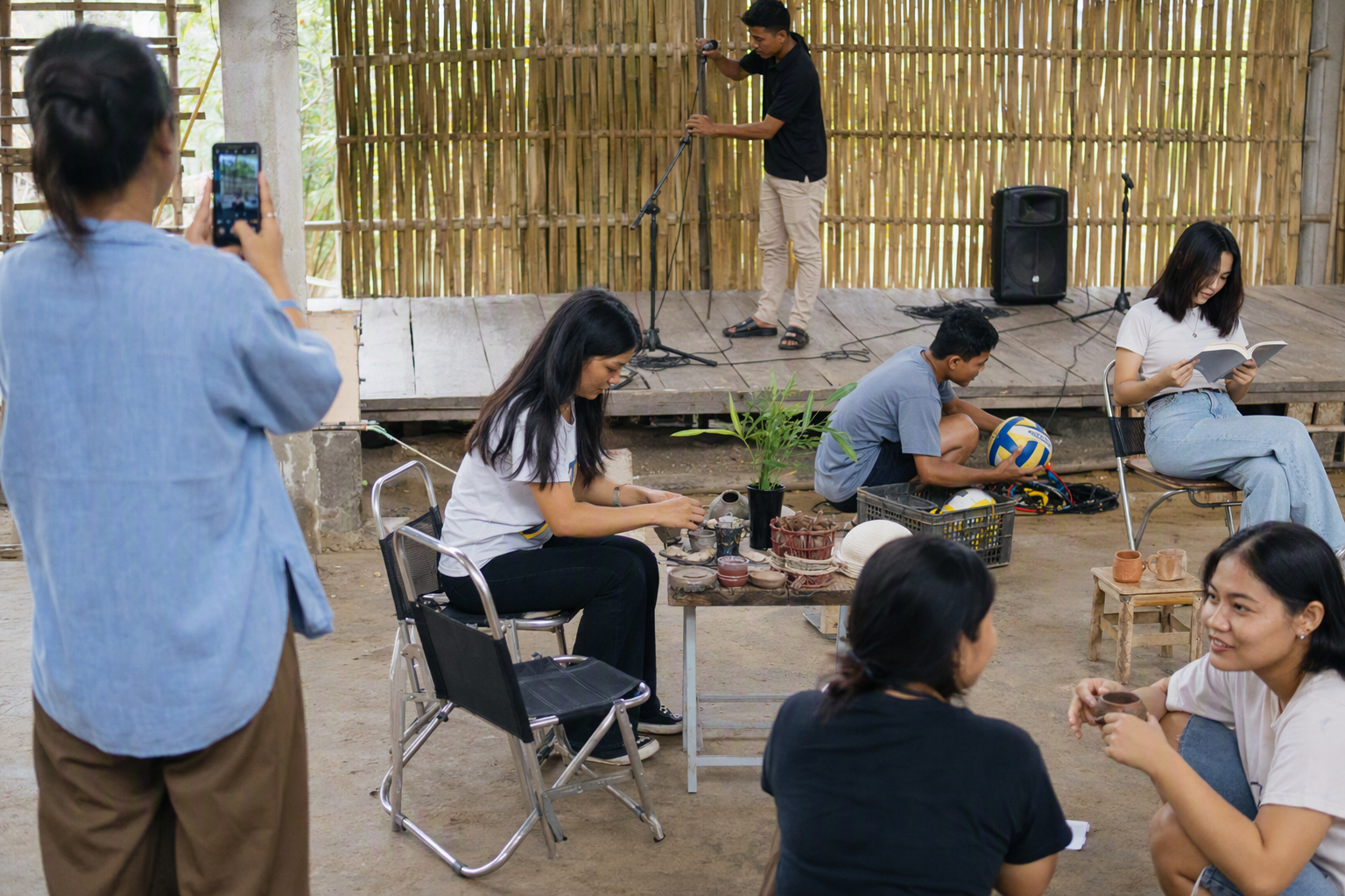 A contemporary shared public space with books, phones, tea, transport, and green ridges beyond
